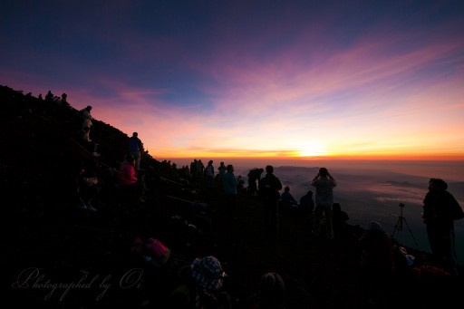 富士山山頂でご来光を待つ人々の写真